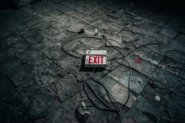 Disruption image showing an exit sign ripped off the wall in a dusty room